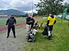Fire personer med diskgolfutstyr står ved en bane med fjell og grønt landskap i bakgrunnen.