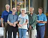 Seks personer står sammen inne i en kirke, mens to holder en pokal og en bokstabel.
