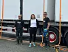 Tre arbeidere står ved siden av en stor lastebil parkert langs veien.