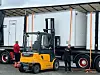 Gul truck ved siden av en semitrailer med to personer som observerer arbeidet.