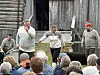 Fire skuespillere opptrer foran en låve, med publikum samlet foran scenen.