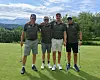 Fire golfspillere står side om side på en golfbane med fjellandskap i bakgrunnen.