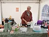 Elsa Kvande står bak et bord med kioskvarer og kaffeutstyr i et hvitt telt.