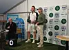 To menn i golfantrekk står på en liten scene.
