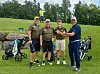 Fire golfspillere står på en golfbane med golftraller og utstyr ved siden av seg.
