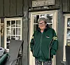 En kvinne står foran en inngang med skiltet «KORTREIST HYGGE» på en mørkegrønn yttervegg på en hytte.