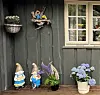 Hagepynt med figurer og blomster og et vindu på en mørk trevegg.
