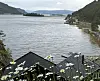 Fjell og fjord med blomster i forgrunnen og toppen av to små bygninger