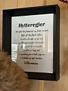 Innrammet plakat med tekst med overkriften 'Hytteregler' på vegg.