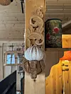 Utskåret tredekor (vegglysestake?) med kråkebolle (?) i et rom med trepanel.