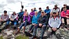 En gruppe turgåere sitter på en steinete fjellrygg i høyfjellet.