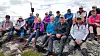 En gruppe turgåere sitter på en steinete fjellrygg i høyfjellet.
