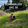 To barn sitter i en gressbakke med trær og en liten bygning i bakgrunnen.