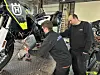 To mekanikere jobber med en motorsykkel i et verksted.
