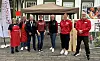 En gruppe personer står under et telt ved et utendørs arrangement på en brosteinsgate.