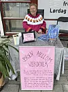Kvinne sitter ved bord med bøker, plakater og et skilt med teksten «Broen mellom verdener».