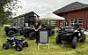 Firehjulinger og terrengkjøretøy står oppstilt på en gressplen ved et hvitt telt og en bygning.