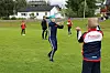 Flere personer deltar i en fotballøvelse på en gressbane, med trenere i forgrunnen.