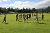 Barn og ungdom spiller fotballtrening på gressbane med kjegler og fjell i bakgrunnen.