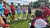 Ungdomsspillere og trener samlet på en fotballbane under en øvelse.