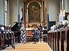 En musikkgruppe opptrer foran alteret i en kirke mens publikum sitter på kirkebenkene.