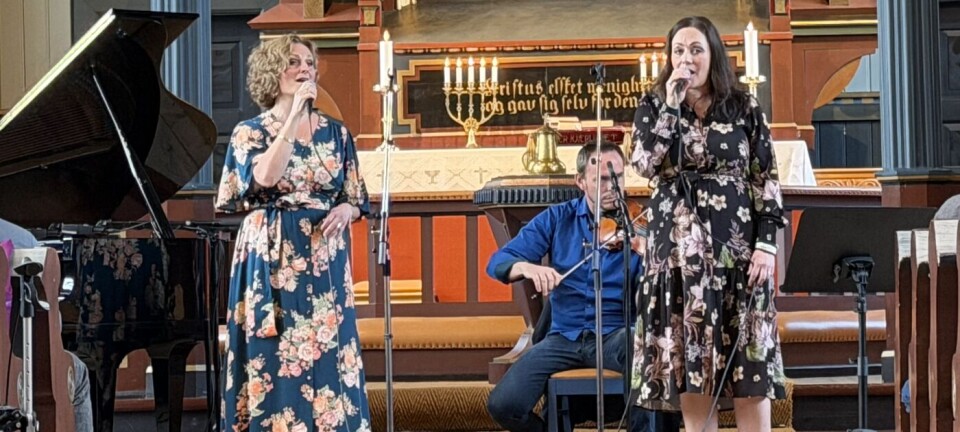 En musikkgruppe opptrer foran alteret i en kirke mens publikum sitter på kirkebenkene.
