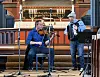 To musikere opptrer i en kirke med altertavle, piano til venstre og benker med publikum på begge sider.
