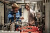 To personer i et laboratorium jobber med instrumenter, slanger og beholdere ved en benk.