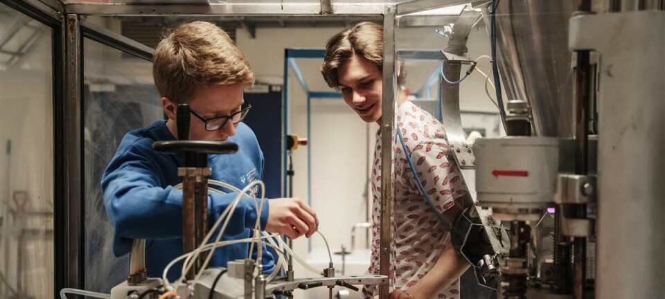 To personer i et laboratorium jobber med instrumenter, slanger og beholdere ved en benk.