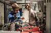 To personer i et laboratorium jobber med instrumenter, slanger og beholdere ved en benk.