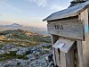 Trekasse merket «URA» ved en steinete fjellrygg med utsikt mot fjellandskap.