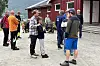 Flere personer står i en gruppe på gårdsplassen foran en rødmalt bygning.
