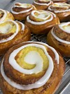 Flere kanelboller med hvit glasur ligger tett på en rist.