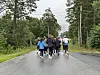 En gruppe mennesker løper på en regnvåt vei med skog på begge sider.