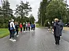 En gruppe mennesker står på en våt vei i et skogsområde.