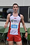 En mann i løpeantrekk med startnummer 350 står ute ved siden av en trillebår.