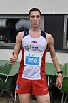 En mann i løpeantrekk med startnummer 350 står ute ved siden av en trillebår.