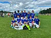En gruppe unge fotballspillere i blå drakter står og sitter samlet på en gressbane.