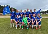 Ungdomslag i blå drakter poserer på en fotballbane med to blå flagg.