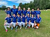 Fotballag i blå drakter står og kneler for lagbilde på en gressbane.