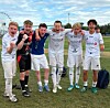 Seks unge fotballspillere står arm i arm på en gressbane med et par flasker og en bag foran seg.