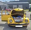 Gul Volkswagen Boble med åpen front og bagasjerommet fullt av ulike gjenstander.