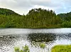 En rolig innsjø med skog rundt og refleksjoner i vannflaten.