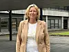 Kvinne står foran en moderne bygning med store vinduer og et overbygg.