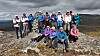 En gruppe turgåere står og sitter på en steinete fjellrygg under mørke skyer.