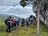 Gruppe med turgåere står på en fjellhylle med utsikt mot dal og fjell.