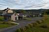 Moderne hus i en boligrekke ved en vei omgitt av grønt landskap og åser.