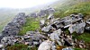 Steinrøys på en grønn fjellskråning i tåke.