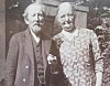 Et eldre par står sammen foran en bygning i et gammelt svart-hvitt fotografi.