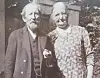Et eldre par står sammen foran en bygning i et gammelt svart-hvitt fotografi.